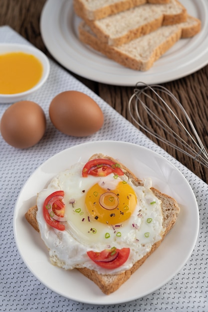 Brood geplaatst met een gebakken ei met tomaten, tapiocameel en gesneden lente-uitjes.