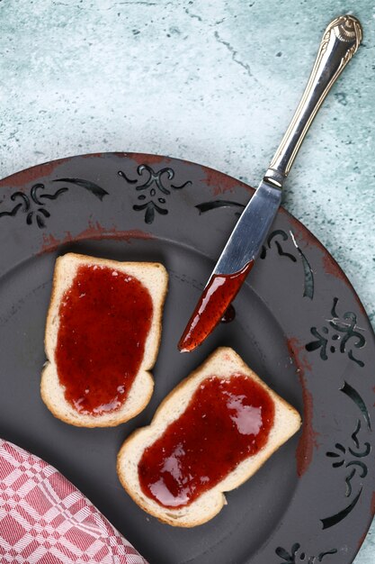 Brood met aardbeijam in grijze plaat.