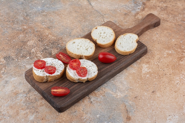 Brood met room en tomatenplakken op houten raad