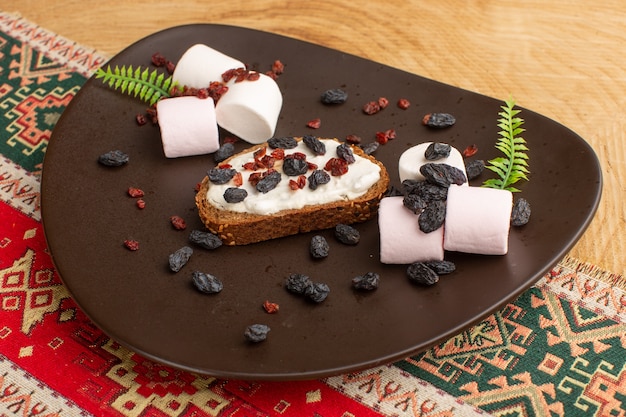 brood toast samen met marshmallows en gedroogd fruit in donkere plaat op hout