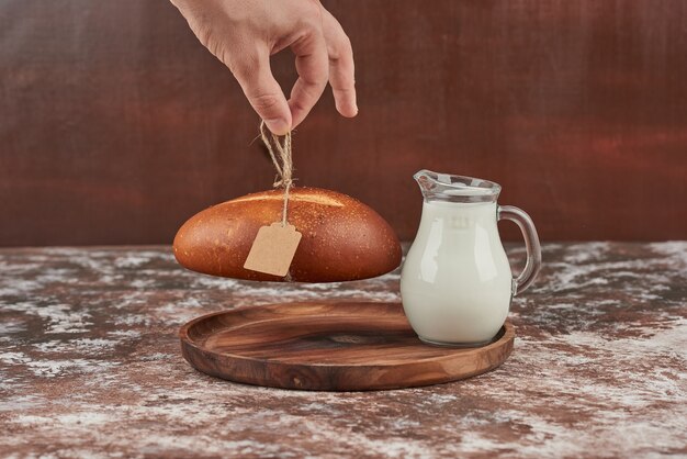 Broodje geïsoleerd op marmer met een pot melk.