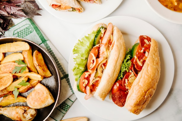 Broodsandwiches met gemengd voedsel erin en gegrilde kip met aardappelen in de pan.