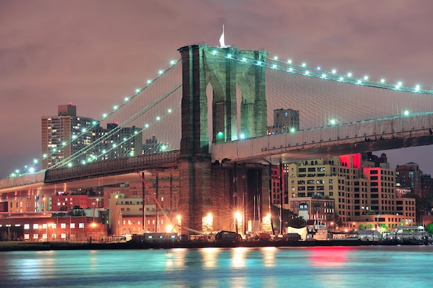 Brooklyn Bridge over East River 's nachts in New York City Manhattan met lichten en reflecties.