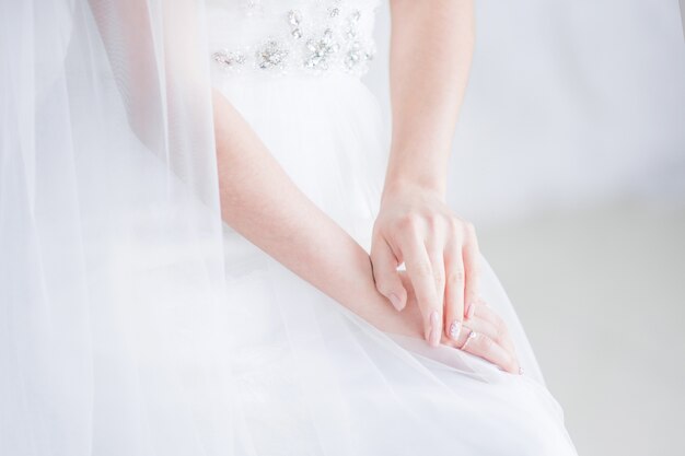 Bruid houdt haar handen gekruist op de knieën