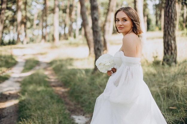 Bruid in trouwjurk in bos