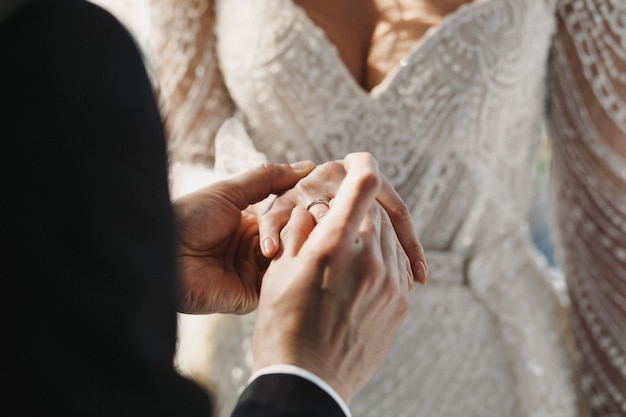 bruidegom draagt een trouwring aan de vinger van de bruid