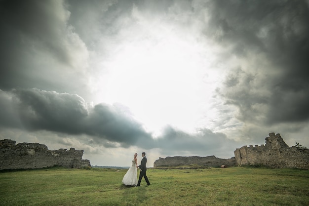 Bruidegom en bruid wandelen met ruïnes achtergrond