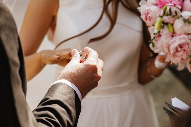 Bruidegom zet trouwring op de hand van de bruid