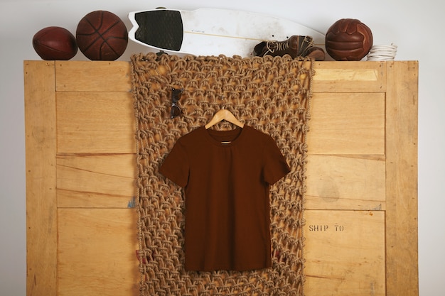 Bruin basic katoenen t-shirt gepresenteerd in een rustiek interieur met vintage leren speelballen erop