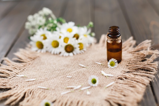 Bruine flessen met oliën, groen en bloemen liggen op bruin servet