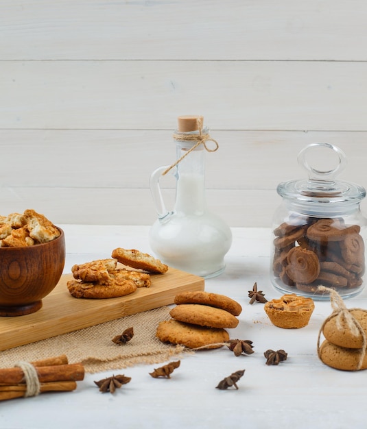 Bruine koekjes in een glazen pot met een kan melk, koekjes en kaneel