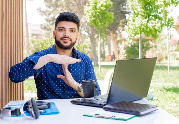 Brunette aziatische jongen met baard zittend aan het werk met stop