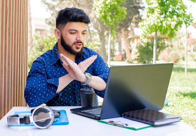 Brunette Aziatische jongen zit aan tafel buiten te werken