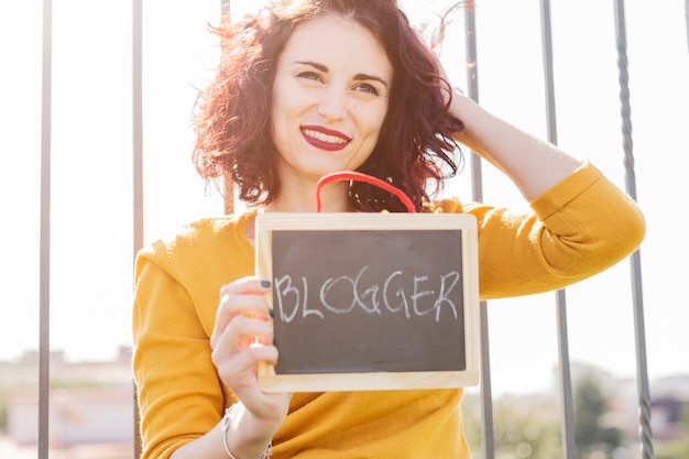 Gratis foto brunette blogger die bord toont aan de camera