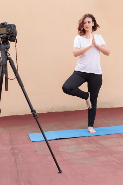 Brunette blogger die yogaroutine opneemt