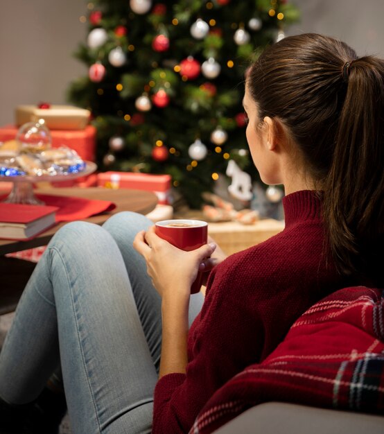 Brunette die een kop met een Kerstmisachtergrond bekijkt