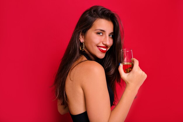 Brunette gelukkig meisje lachend naar camera met een glas champagne.