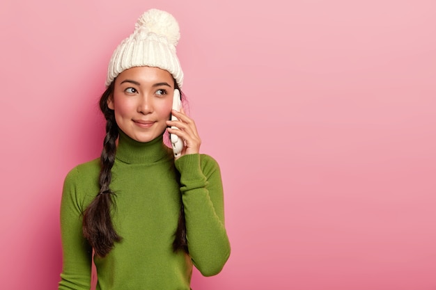brunette hipster vrouw bellen via moderne gadget op roze achtergrond