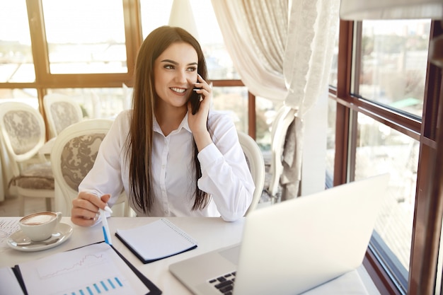 Brunette langharige vrouw manager praat op de mobiele telefoon ar de receptie