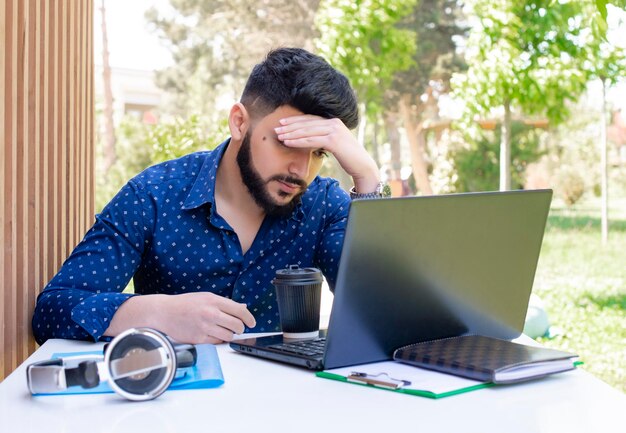 Brunette man met baard zittafel werken met behulp van laptop