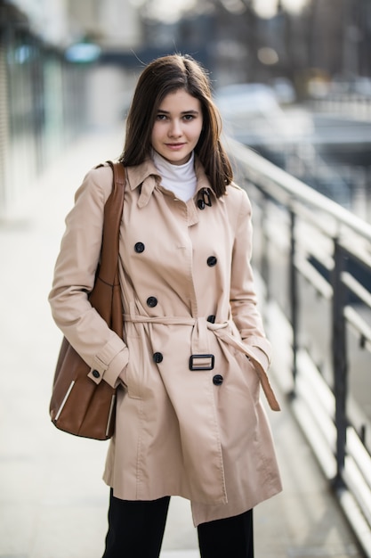 Brunette meisje op straat in koffie jas en bruin lederen tas