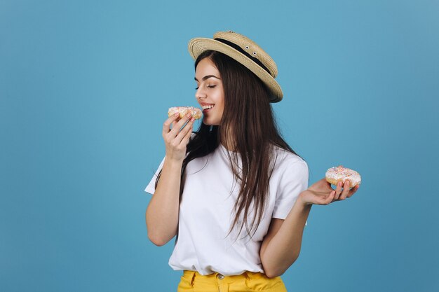 Brunette meisje smaakt een donut poseren in een hoed