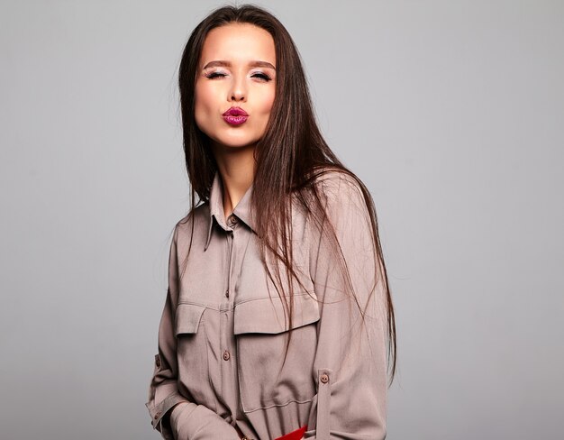 brunette model in beige stijlvolle kleding met lichte make-up en rode lippen