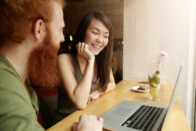 Brunette vrouw en gember man zitten in café