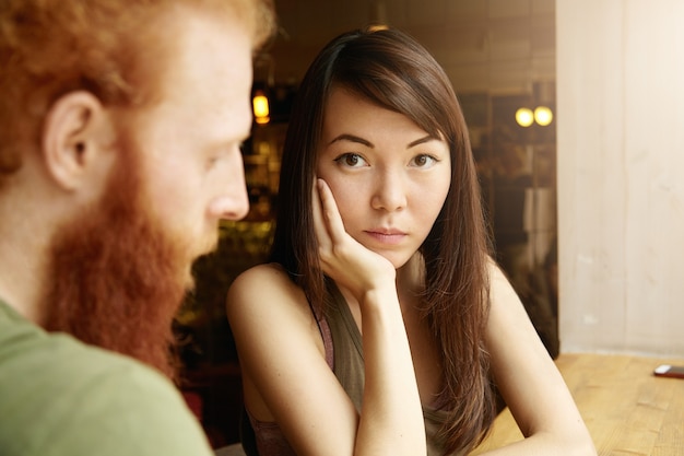 Brunette vrouw en gember man zitten in café