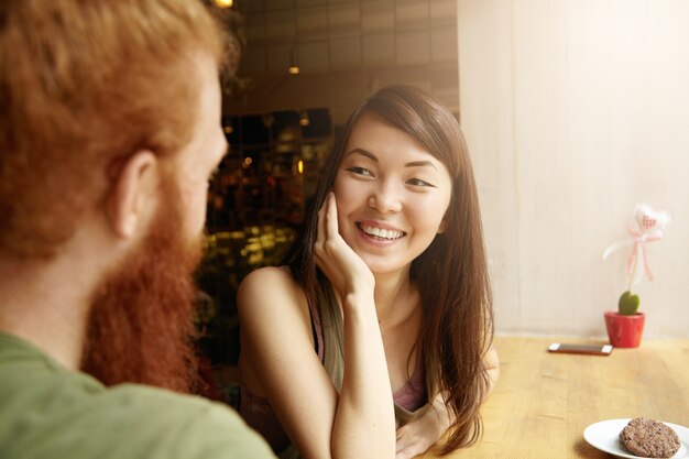 Brunette vrouw en gember man zitten in café