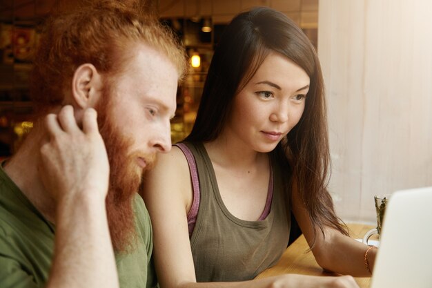 Brunette vrouw en gember man zitten in café