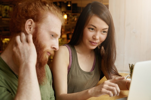 Gratis foto brunette vrouw en gember man zitten in café