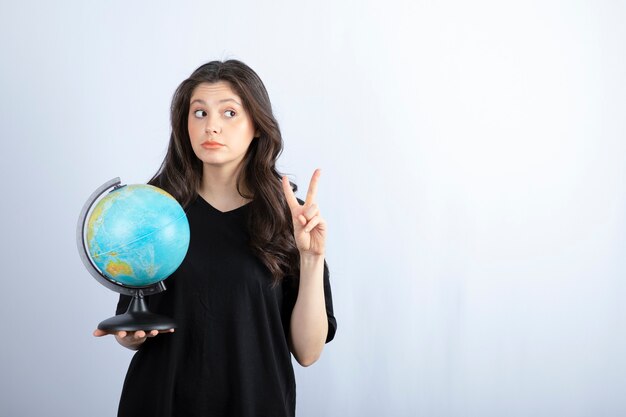 Brunette vrouw met lang haar wereldbol te houden en poseren.