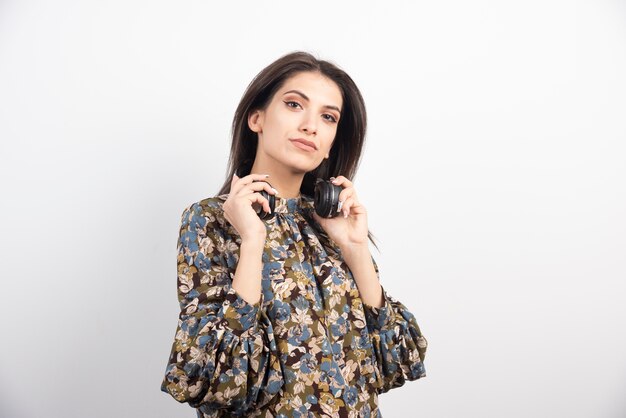 Brunette vrouw poseren met koptelefoon op witte achtergrond.