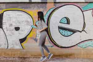 Gratis foto brunette vrouw rennen tegen betonnen muur