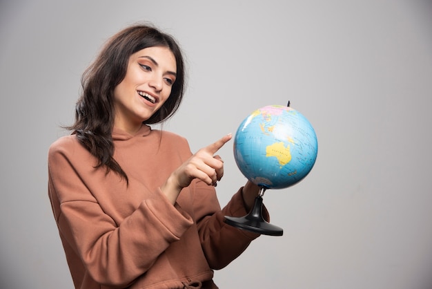 Brunette vrouw wijzend op kleine plaats op wereldbol