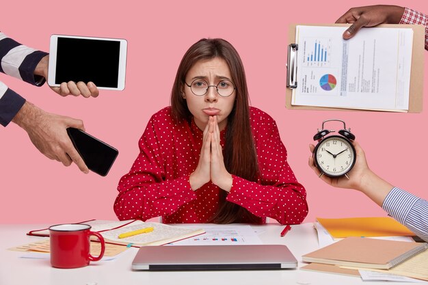 Brunette vrouw zittend aan een bureau omringd met gadgets en papieren