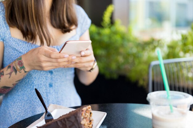 Buik van influencer die voedselverhalen online deelt via smartphone in café