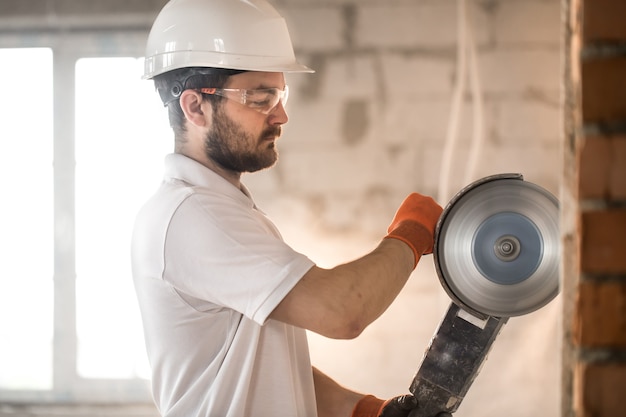 Builder werkt met een professionele haakse slijper om stenen te snijden