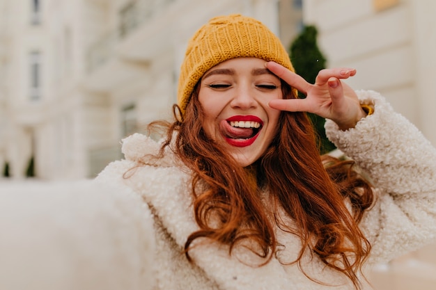 Buiten foto van lachende geweldig meisje genieten van de winter. Aantrekkelijk gember vrouwelijk model selfie maken.