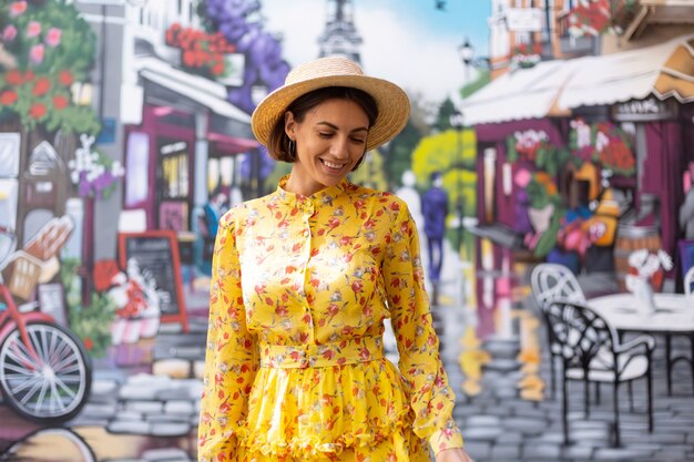 Buiten mode portret van vrouw in gele zomerjurk op straat kleurrijke muur