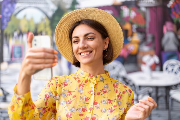 Buiten mode portret van vrouw in gele zomerjurk op straat kleurrijke muur