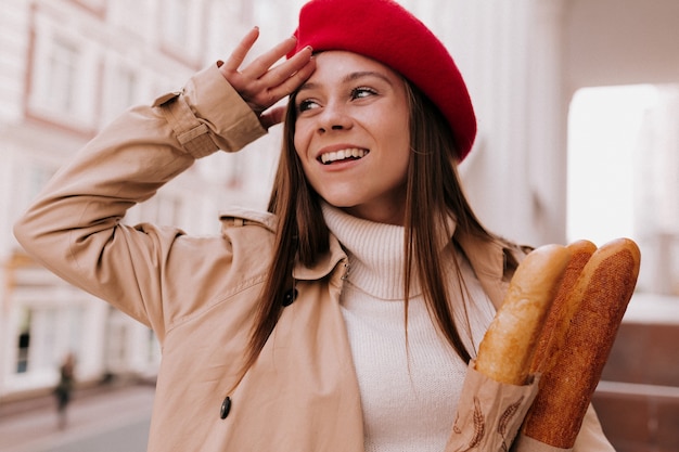 Buiten portret van jonge aantrekkelijke Franse vrouw met lang lichtbruin haar, gekleed in rode baret