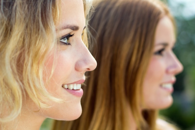 Gratis foto buiten portret van twee mooie jonge vrouwen poseren in het park