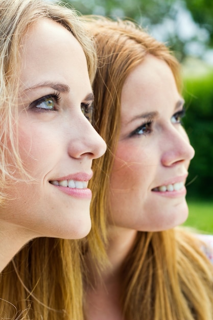 Gratis foto buiten portret van twee mooie jonge vrouwen poseren in het park