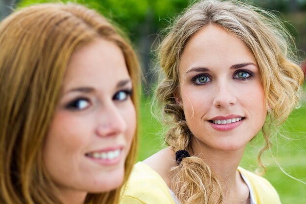 Buiten Portret van twee mooie jonge vrouwen poseren in het park