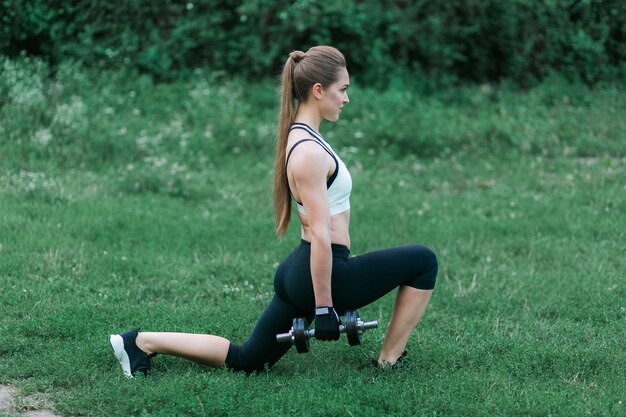 Buiten trainen. Mooie blonde atletische vrouw die spieren met domoren pompen