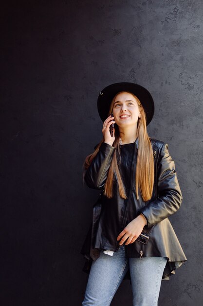 Buiten zomer portret van stijlvolle meisje gesteld in zonnige dag op straat met telefoon