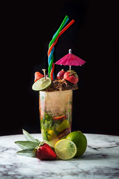 Buitensporige zomercocktail met kleurrijk fruit en accesorices.