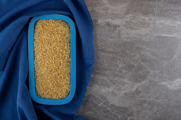 Bulgur in het bakje op de handdoek, op het marmeren oppervlak